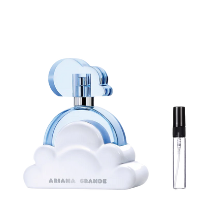 Jasnoniebieski flakon perfum Ariana Grande Cloud w kształcie okręgu na białej podstawie przypominającej chmurę z niebieskim korkiem, obok którego znajduje się przezroczysta, szklana fiolka odlewki z czarnym atomizerem. – ODVARO