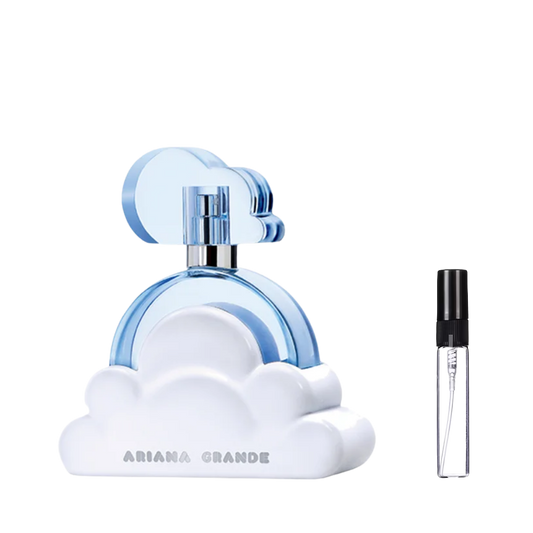Jasnoniebieski flakon perfum Ariana Grande Cloud w kształcie okręgu na białej podstawie przypominającej chmurę z niebieskim korkiem, obok którego znajduje się przezroczysta, szklana fiolka odlewki z czarnym atomizerem. – ODVARO