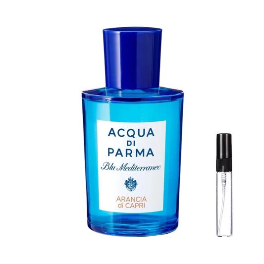 Prostokątny, ciemnoniebieski flakon perfum Acqua di Parma Blu Mediterraneo Arancia di Capri z cylindryczną nakrętką w tym samym kolorze i białą, prostokątną etykietą, prezentowany obok szklanej fiolki odlewki – ODVARO