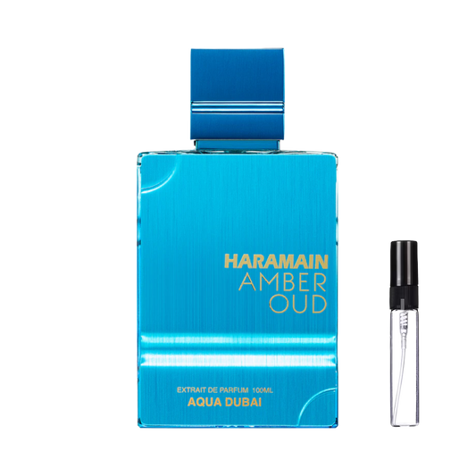 Nowoczesny, błękitny flakon Al Haramain Amber Oud Aqua Dubai z metalicznym wykończeniem i złotymi napisami, obok którego stoi smukła, szklana fiolka odlewki z czarnym atomizerem – ODVARO