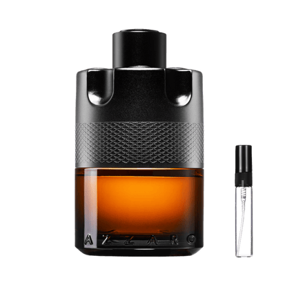 Flakon Azzaro The Most Wanted Parfum w kształcie bębna rewolweru z bursztynowym płynem obok szklanej fiolki odlewki perfum – ODVARO.