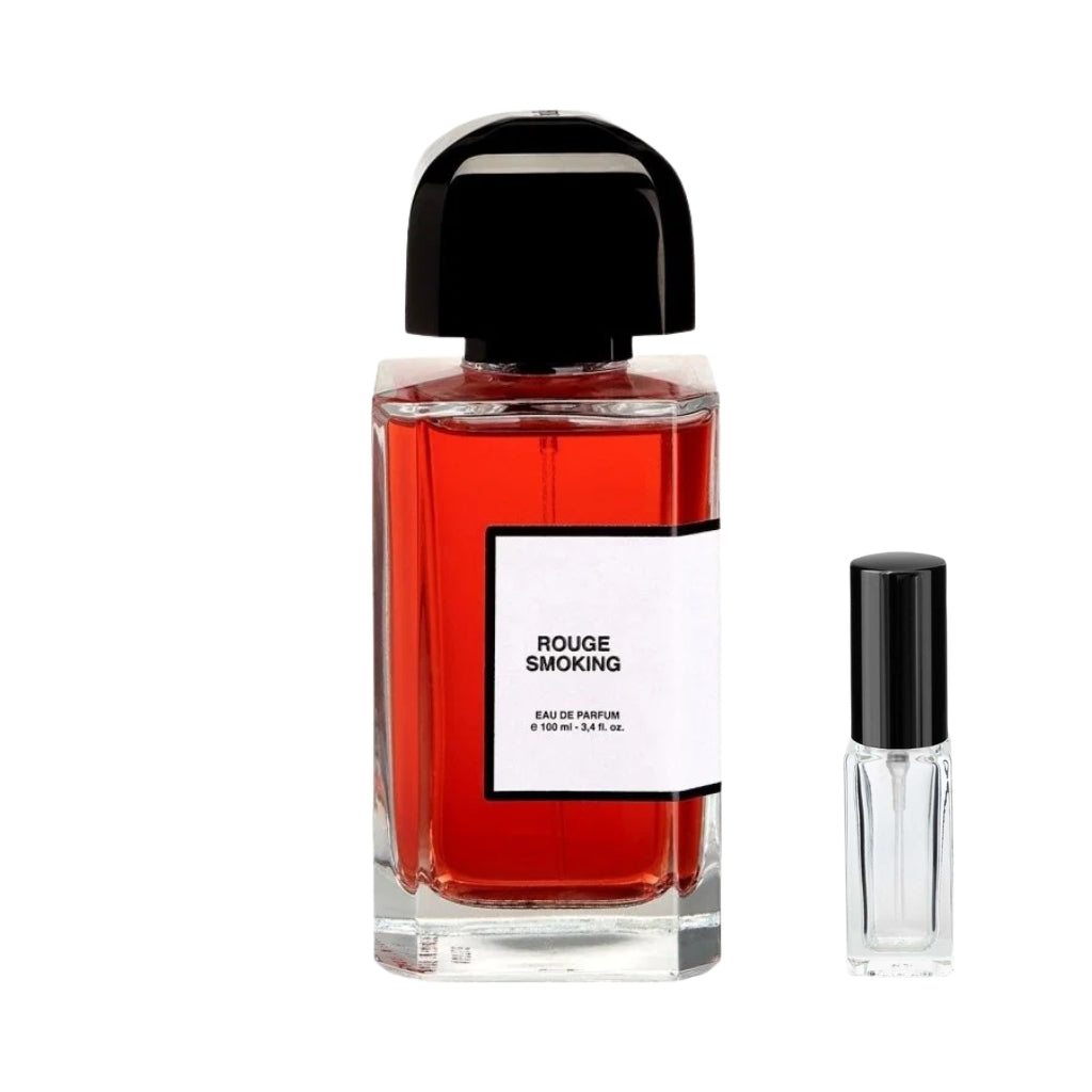Szklany, prostokątny flakon perfum Rouge Smoking BDK Parfums wypełniony czerwonawym płynem, z białą etykietą z czarną ramką i masywnym, czarnym półokrągłym korkiem, a obok niego szklana fiolka odlewki – ODVARO.