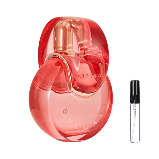 Charakterystyczny flakon perfum Bvlgari Omnia Coral o kształcie połączonych, koralowo-czerwonych pierścieni ze srebrnymi akcentami, prezentowany obok szklanej fiolki odlewki – ODVARO