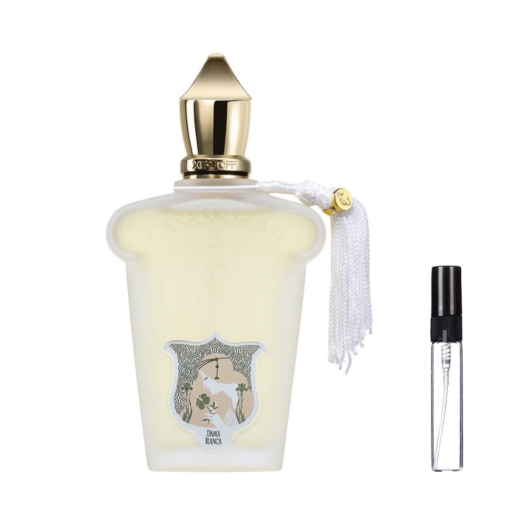 Matowy flakon perfum Casamorati 1888 Dama Bianca w stylu vintage, ze złotym spiczastym korkiem, białą ozdobną kitką, etykietą z profilem kobiety oraz szklana fiolka odlewki – ODVARO.