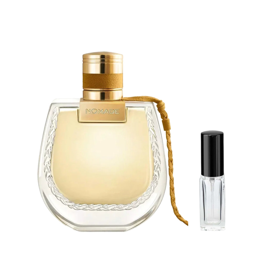 Zaokrąglony, szklany flakon perfum Chloé Nomade Jasmin Naturel ze złotym płynem, zwieńczony złotym korkiem z brązowym rzemykiem. Obok elegancka szklana fiolka odlewki z minimalistyczną etykietą – ODVARO.