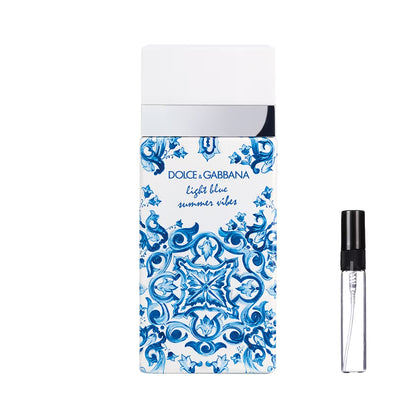 Prostokątny flakon perfum Dolce&Gabbana Light Blue Summer Vibes ozdobiony niebiesko-białym wzorem majoliki, ze srebrnym detalem i gładkim białym korkiem, a obok widoczna szklana fiolka odlewki – ODVARO.