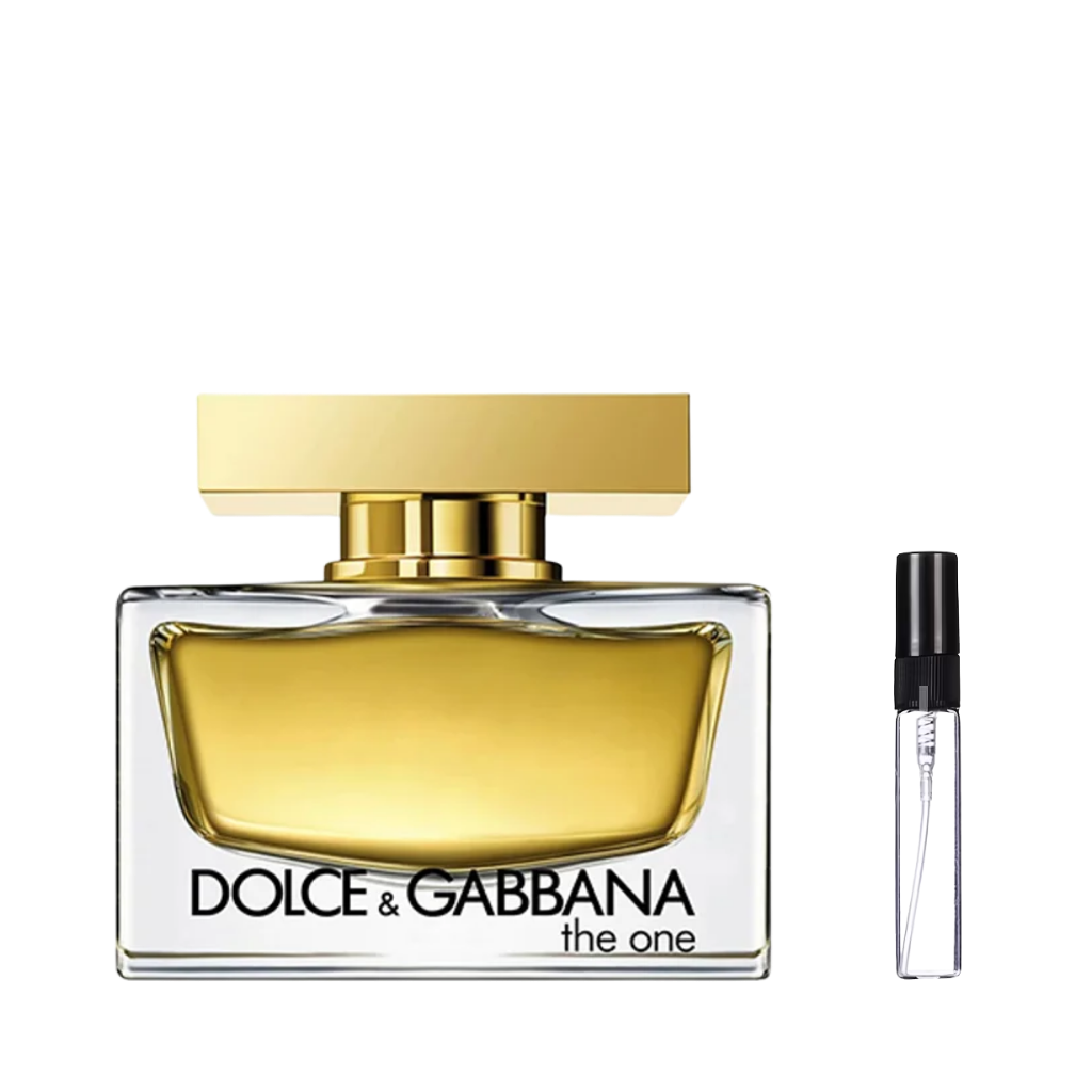 Elegancki, prostokątny flakon perfum z grubego szkła wypełniony złotym płynem, ze złotym, masywnym korkiem i czarnym napisem, obok którego znajduje się przezroczysta, szklana fiolka odlewki z czarnym atomizerem. – ODVARO