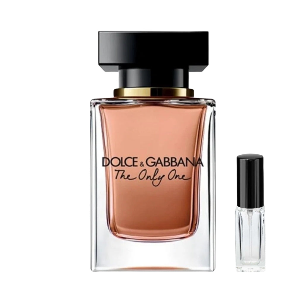 Szklany, prostokątny flakon damskich perfum Dolce&Gabbana The Only One wypełniony brzoskwiniowym płynem, z masywnym czarnym korkiem ozdobionym złotym pierścieniem, a obok niego szklana fiolka odlewki – ODVARO.