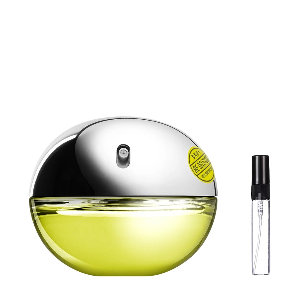 Flakon perfum DKNY Be Delicious w kształcie jabłka, z zielonym, szklanym dołem, srebrnym, metalicznym korkiem i owalną naklejką, obok którego leży szklana fiolka odlewki – ODVARO.