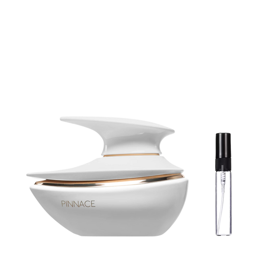 Biały, nowoczesny flakon perfum o futurystycznym, opływowym kształcie ze złotym pierścieniem i napisem PINNACE oraz szklana fiolka odlewki – ODVARO