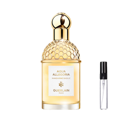 Cylindryczny flakon ze złotą siateczką w kształcie plastra miodu i kulistym korkiem, wypełniony złocistym płynem, obok szklana fiolka odlewki na perfumy – ODVARO