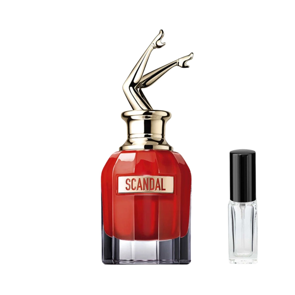 Czerwony, fasetowany flakon damskich perfum Scandal Le Parfum Jean Paul Gaultier z ozdobnym złotym korkiem w kształcie uniesionych kobiecych nóg oraz złotą plakietką na froncie, a obok niego szklana fiolka odlewki – ODVARO.