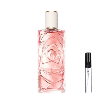 Smukły, prostokątny szklany flakon perfum Lancôme Ôver The Top z łososiowo-różowym płynem, ozdobiony trójwymiarowym motywem róży widocznym przez szkło, z teksturowanym białym korkiem ze złotą obwódką. W ofercie dostępna również poręczna szklana fiolka odlewki – ODVARO
