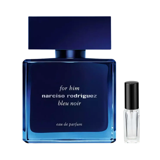 Ciemnoniebieski, prostokątny flakon perfum Narciso Rodriguez for Him Bleu Noir z szerokim, matowym korkiem w tym samym kolorze i jasnymi napisami na froncie, obok którego prezentowana jest szklana fiolka odlewki. – ODVARO