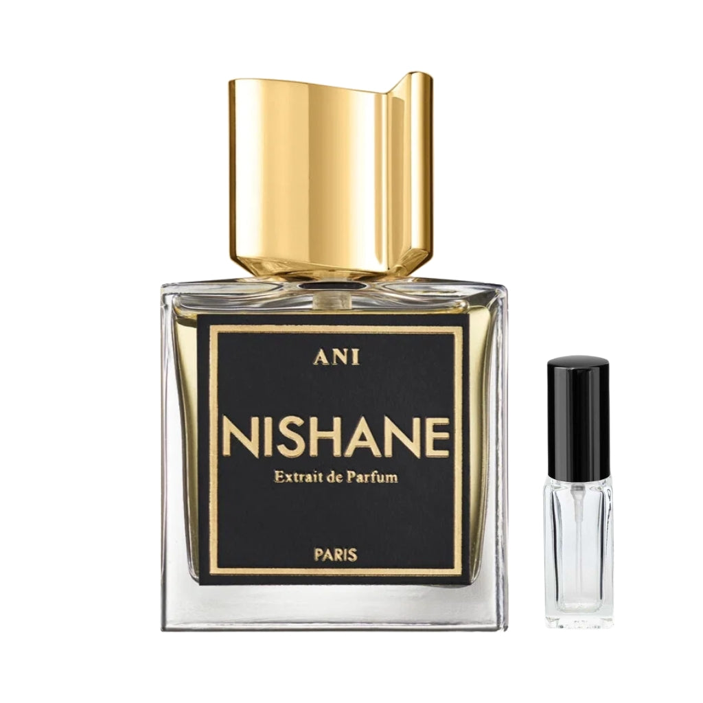 Przezroczysty, kwadratowy flakon perfum Nishane Ani z elegancką, czarną etykietą ze złotymi napisami i wyrazistym, asymetrycznym złotym korkiem, obok szklana fiolka odlewki – ODVARO.