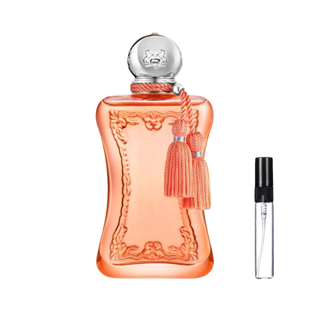 Elegancki, brzoskwiniowy flakon perfum Parfums de Marly Athénaïs o wyprofilowanym kształcie z ozdobnymi tłoczeniami, zwieńczony srebrnym korkiem i chwostami, obok prezentuje się szklana fiolka odlewki – ODVARO