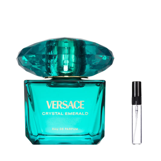 Szmaragdowy, szklany flakon perfum Versace Crystal Emerald z masywnym korkiem w kształcie klejnotu i złotymi napisami, obok którego znajduje się szklana fiolka odlewki – ODVARO.