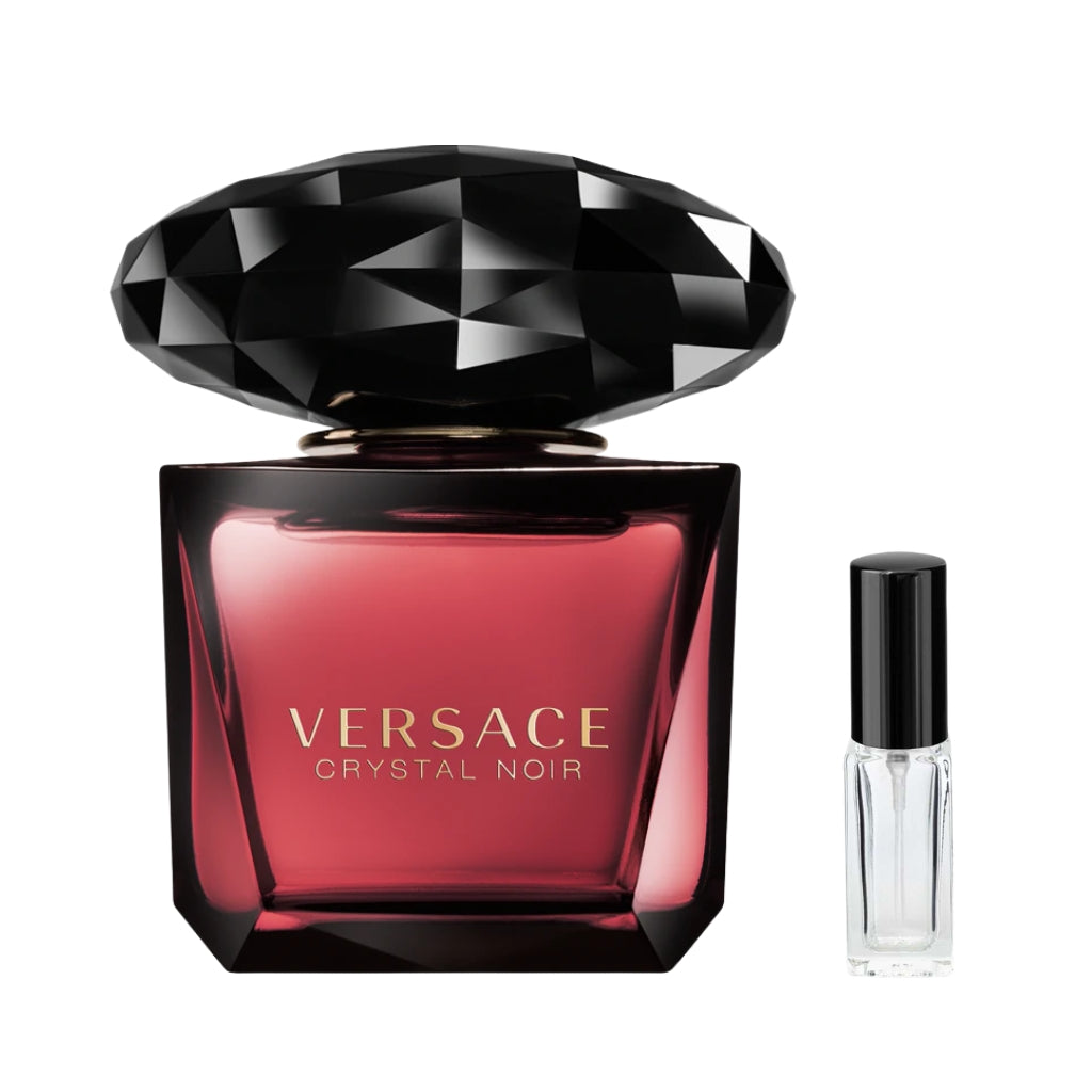 Ciemnośliwkowy, szklany flakon damskich perfum Versace Crystal Noir z masywnym korkiem przypominającym czarny, oszlifowany klejnot oraz złotymi napisami na froncie, a obok niego szklana fiolka odlewki – ODVARO.